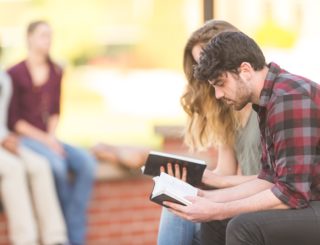 man and woman sitting and looking at bibles