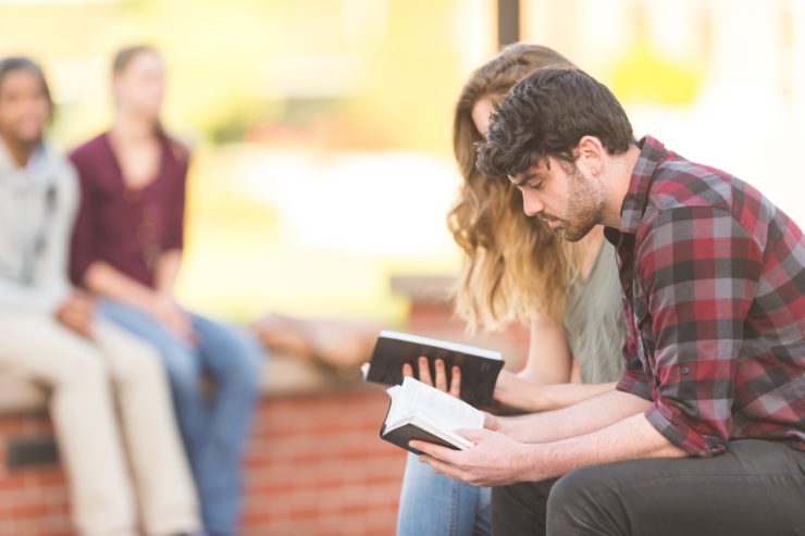 man and woman sitting and looking at bibles