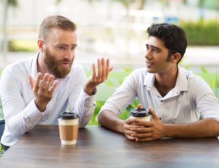 two men talking at table outside