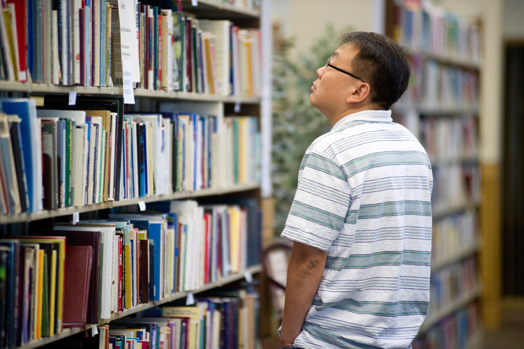 man looking at bookshelves in library