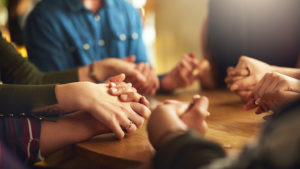 group of people holding hands around table