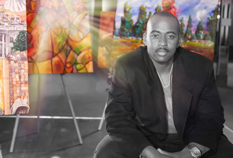 man sitting in black and white in front of colorful artwork