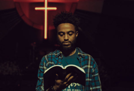 male student looking at bible with glowing cross