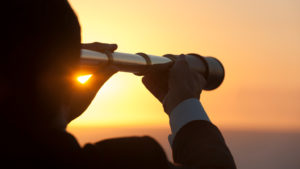 person looking into sky with telescope