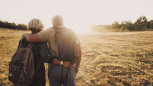 Older couple pictured from the back with arms around each other
