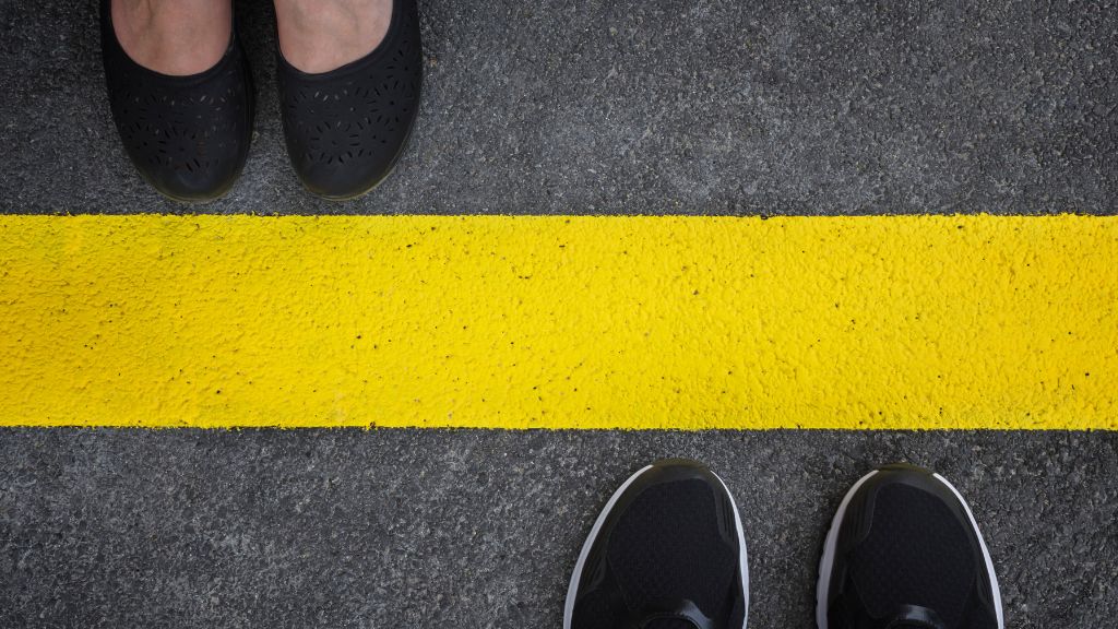 two pairs of shoes facing each other across yellow line on road