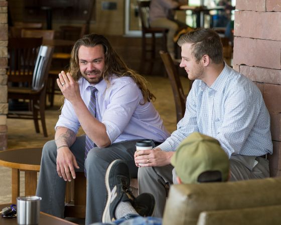 two men sitting next to each other talking