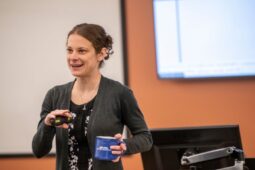 female professor standing in class holding coffee mug