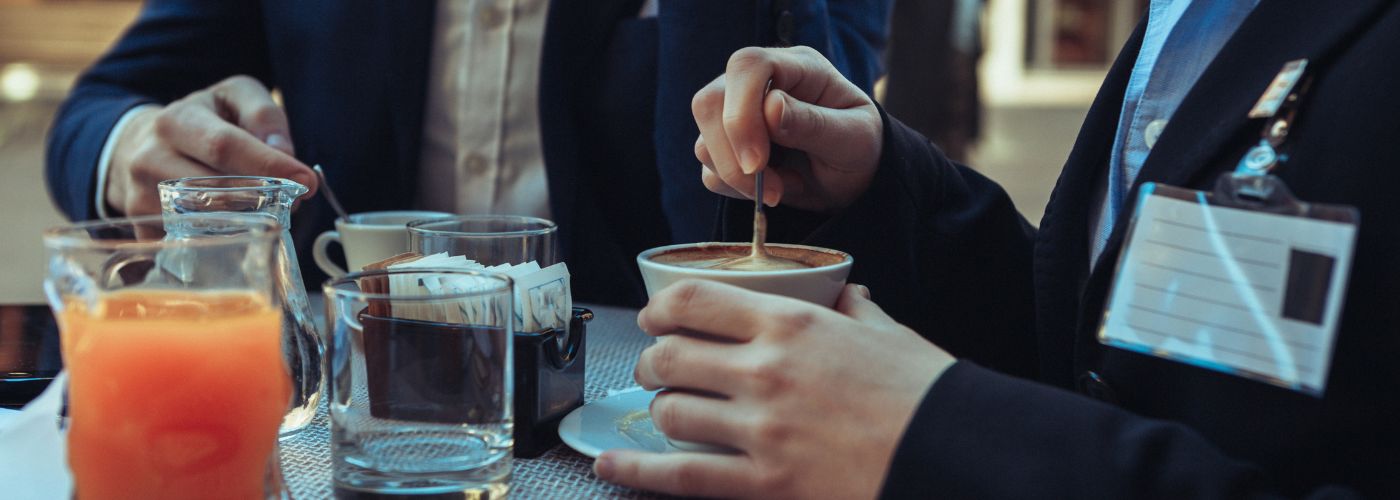 two men stirring coffee over table